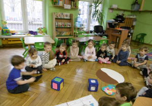 Dzieci siedzą w kole.