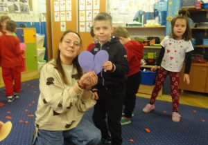 Nauczycielka i chłopiec trzymają fioletowe serce z papieru.