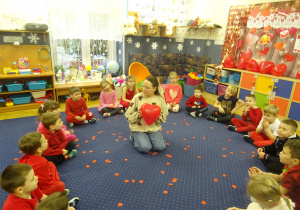 Nauczcielka siedzi na dywanie i trzyma balon w kształcie serca.