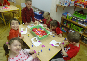 Inna grupa dzieci siedzi przy stoliku.