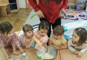 Dziewczynka wlewa wodę do mąki.