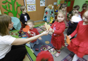 Nauczycielka podaje dziecku papierowe serce.