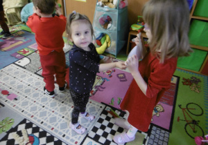 Dziewczynka stoi obok dziewczynki z papierowym sercem.