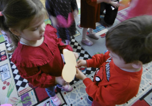 Dwoje innych dzieci stoi z papierowym sercem.