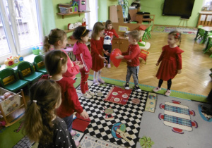 Chłopiec podaje innemu dziecku czerwony balon.