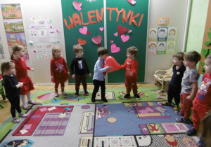 Inny chłopiec podaje kolejnemu dziecku czerwony balon.