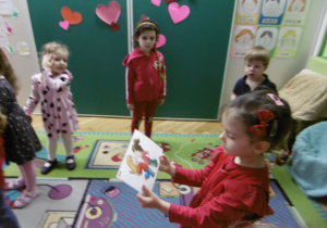 Dziewczynka siedzi na dywanie.