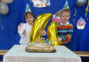 Dwoje solenizantów stoi przy cieście.