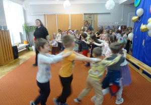 Kolejne dzieci podczas innej zabawy ruchowej trzymają się za ramiona.