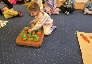 Dziewczynka wkłada przysmak dla psa pod pluszową marchewką.