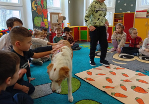 Dzieci głaszczą psa.