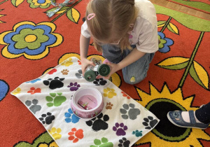 Dziewczynka nalewa wodę dla psa.