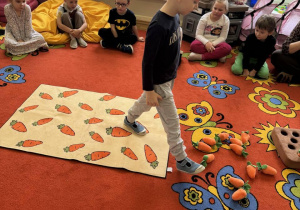 Chłopiec idzie po marchewkowym dywanie.