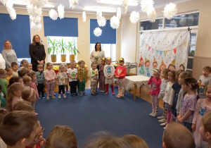 Dzieci stoją w kole i śpiewają sto lat.