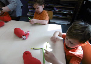 Dwóch chłopców próbuje nawinąć drucik na drewniany element.