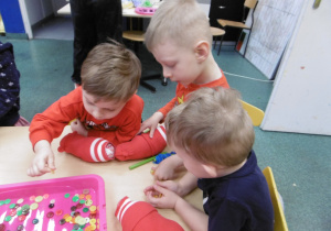 Troje dzieci siedzi przy stoliku.