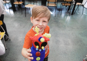 Chłopiec trzyma w ręku wykonaną przez siebie skarpetę.