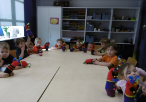 Grupa dzieci siedzi przy stole z wykonanymi przez siebie pracami.