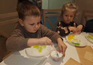 Chłopiec w brązowej bluzie miesza bitą śmietanę.