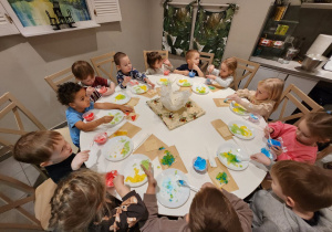 Dzieci siedzą przy okrągłym stole z galaretkami na talerzach.