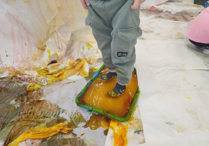 Chłopiec w skarpetkach stoi w misce z masą.