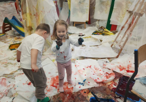 Dziewczynka pokazuje rączki, które są pokryte farbą.