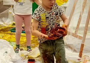 Chłopiec w ubraniach pokrytych farbami.