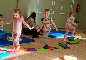 Dzieci idą po ścieżce sensorycznej.