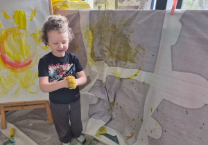 Chłopiec maluje farbami.