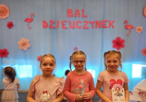 Dziewczynki w różowych strojach stoją z nagrodami.