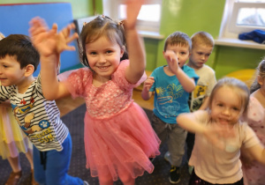 Dziewczynka w różowej sukience podskakuje.