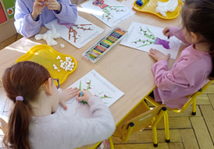 Trzy dziewczynki siedzą przy stoliku.