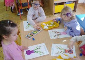 Trzy inne dziewczynki siedzą przy stoliku.