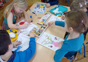 Troje dzieci siedzi przy stoliku.