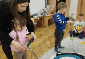 Dwoje innych dzieci trzyma sznurki w ręku.