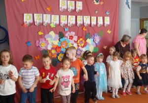 Grupa dzieci stoi obok siebie na tle dekoracji.