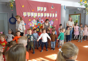 Grupa dzieci idzie jedno za drugim w tańcu.