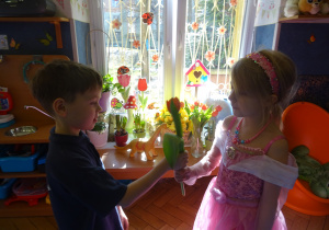 Chłopiec wręcza dziewczynce kwiatek.