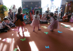 Trzy dziewczynki podczas zabaw na dywanie.