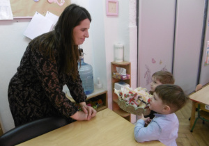 Dwoje dzieci wręcz kawiaty nauczycielce.