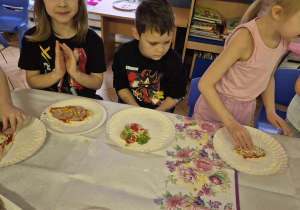 Dzieci układają ciasto na talerzykach.