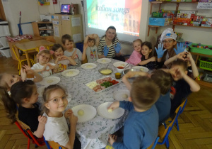 Grupa dzieci siedzi przy stole.