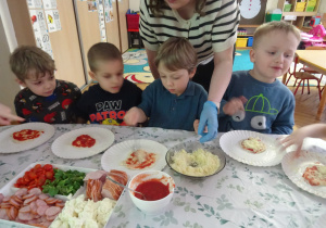 Czworo dzieci siedzi przy swoich kawałkach pizzy.