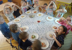 Grupa dzieci siedzi przy stole.