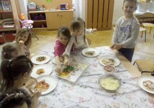 Dzieci podczas komponowania swoej pizzy.