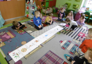 Dzieci siedzą na dywanie podczas wspólnych zajęć.