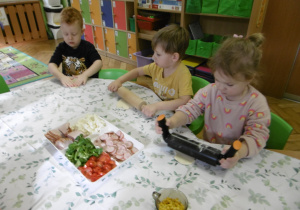 Troje dzieci wałkuje swoje kawałki ciasta.