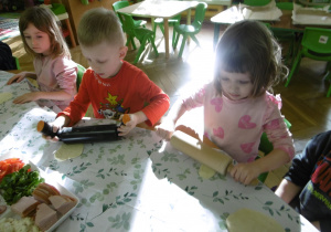 Dwoje dzieci wałkuje swoje kawałki ciasta.