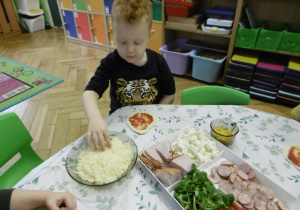 Chłopiec nakłada swoje dodatki na ciasto.