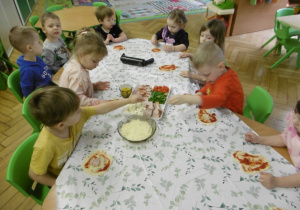 Grupa dzieci siedzi wspólnie przy stole.